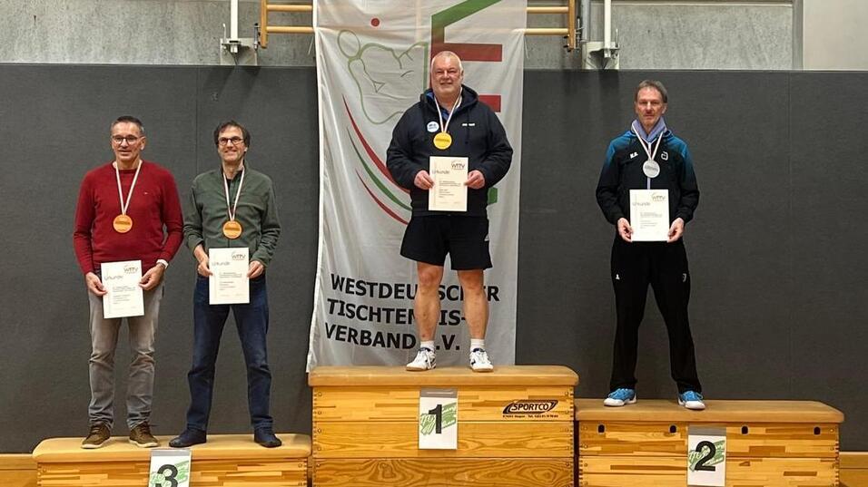 Vier Männer auf Treppchen bei einer Tischtennisveranstaltung, jeweils mit Medaillen und Urkunden, vor einem Verbandbanner.