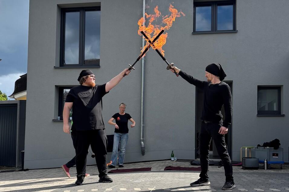 Auf dem Bild sieht man zwei junge Männer mit brennenden Feuerschwertern