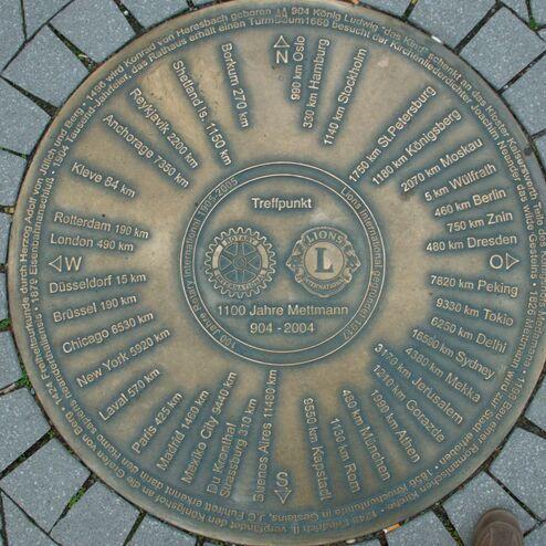 Bronzene Gedenktafel mit Entfernungsangaben zu verschiedenen Städten, um einen zentralen Punkt in Mettmann.