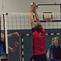 Zwei Spieler im Volleyball springen zur Ballabwehr am Netz, während ein weiterer Spieler beobachtet.