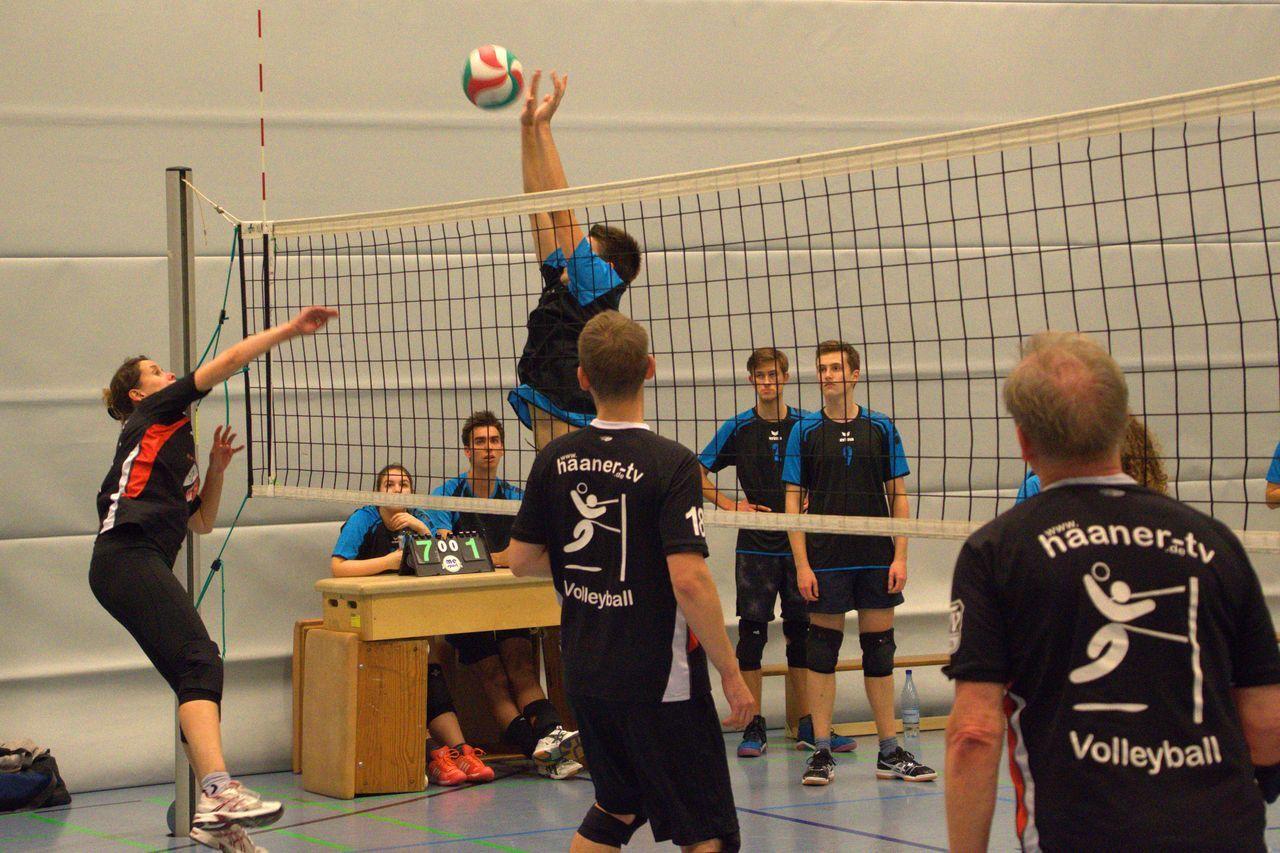 Volleyballspiel in der Halle: Spielerinnen und Spieler fokussieren sich auf das Netz und den Ball während des Spiels.