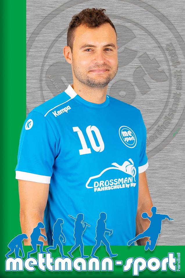 Portrait eines Mannes in blauem Handballtrikot mit der Nummer 10, lächelnd vor grauem Hintergrund.