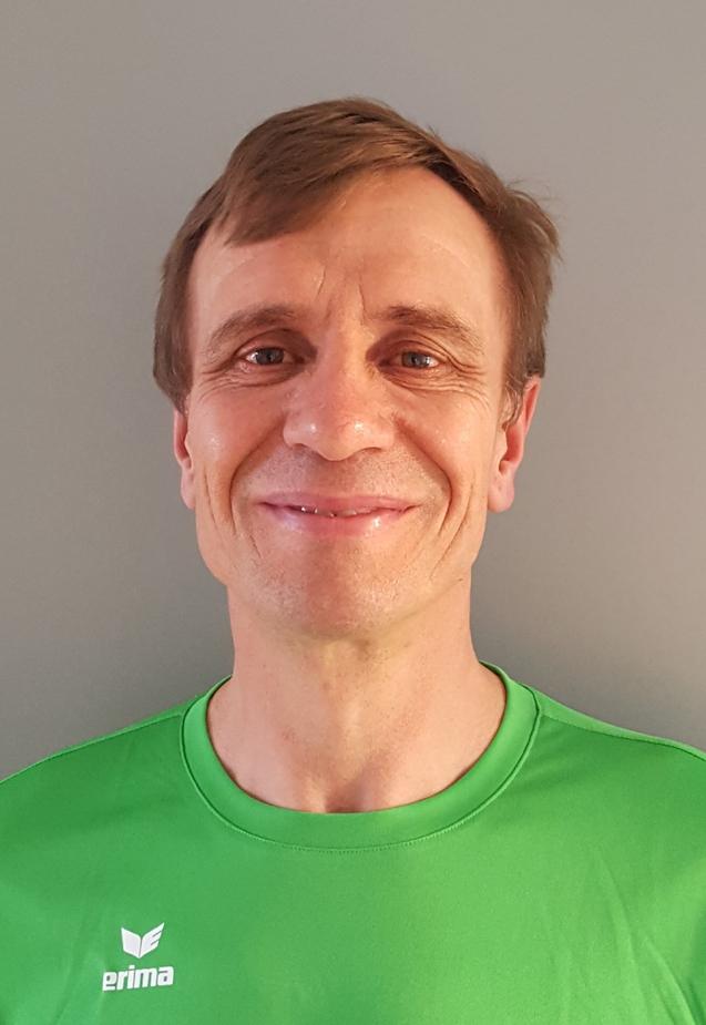 Lächelnder Mann in einem grünen Sportshirt vor einem grauen Hintergrund.