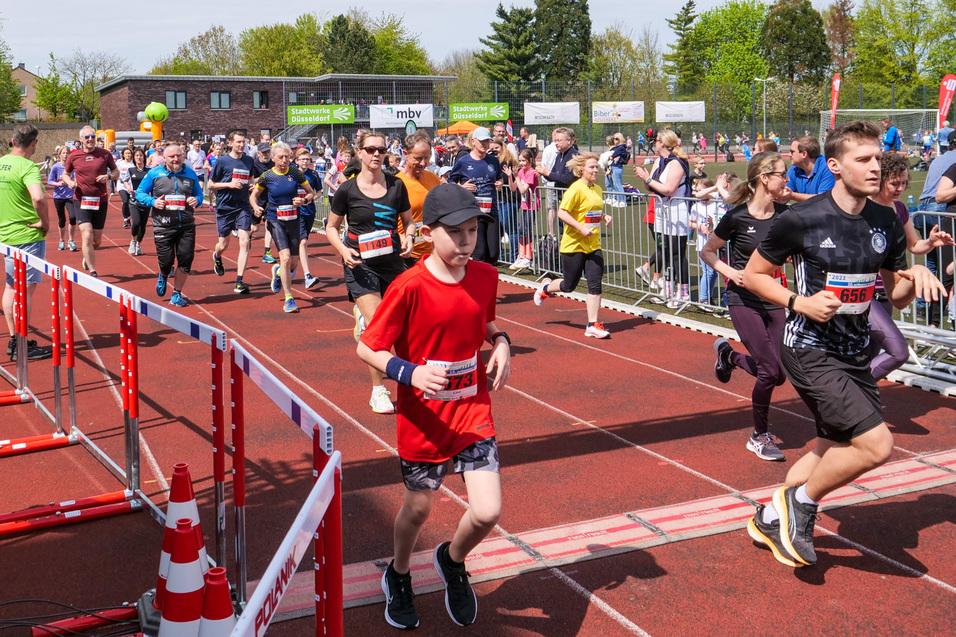 Sportveranstaltung mit Läufern beim Start eines Wettlaufs, umgeben von Zuschauern und einer begrünten Kulisse.