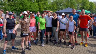 Vor dem 10km-Schnupperlauf Gruppe von Läufern in Sportkleidung posiert lächelnd vor einer Veranstaltung im Freien, umgeben von grünem Laub.